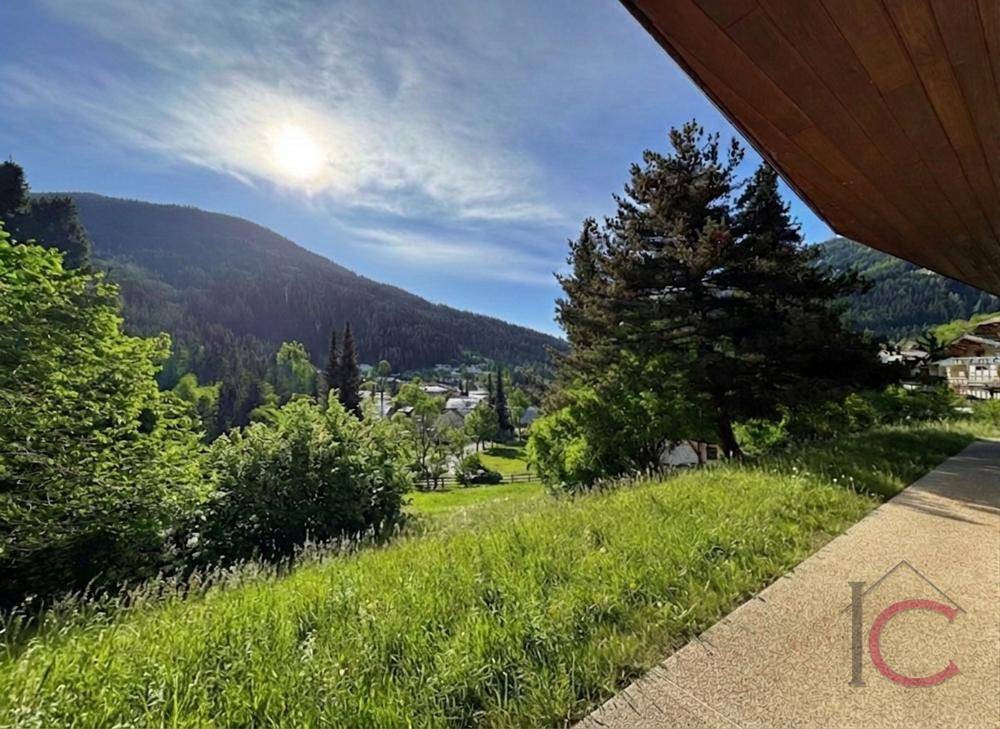 Sonniger Ausblick auf die grüne Berglandschaft und das Tal von einer erhöhten Position.