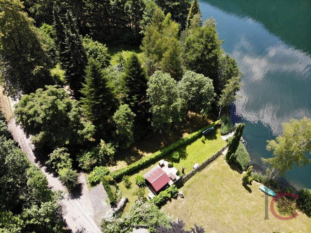 Luftaufnahme des Anwesens am Seeufer, umgeben von Wald und mit eigenem Gartenbereich.