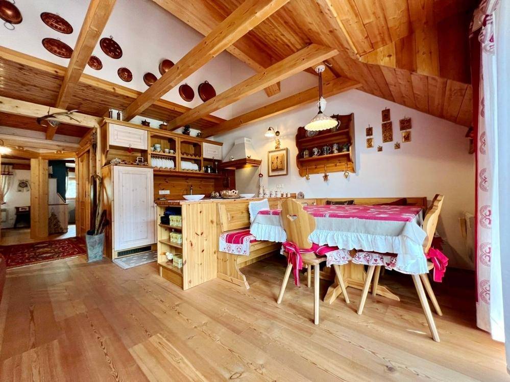 Gemütliche Wohnküche im Chalet-Stil mit viel Holz, sichtbaren Deckenbalken und integriertem Essbereich.