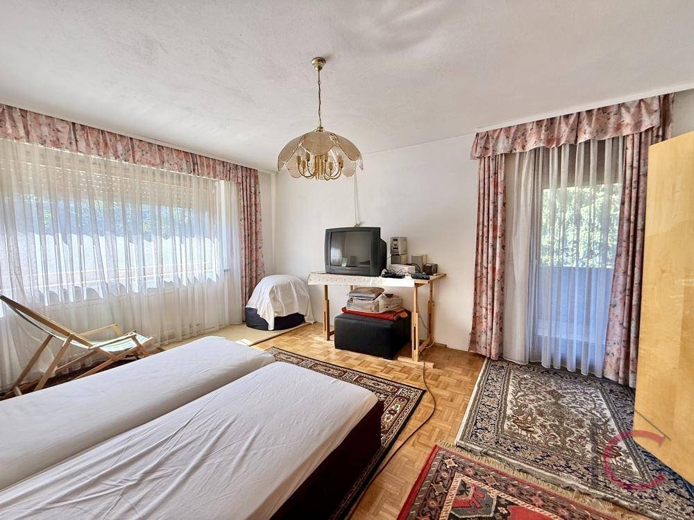 Schlafzimmer mit zwei Einzelbetten, Holzparkettboden und Zugang zu einem Balkon.