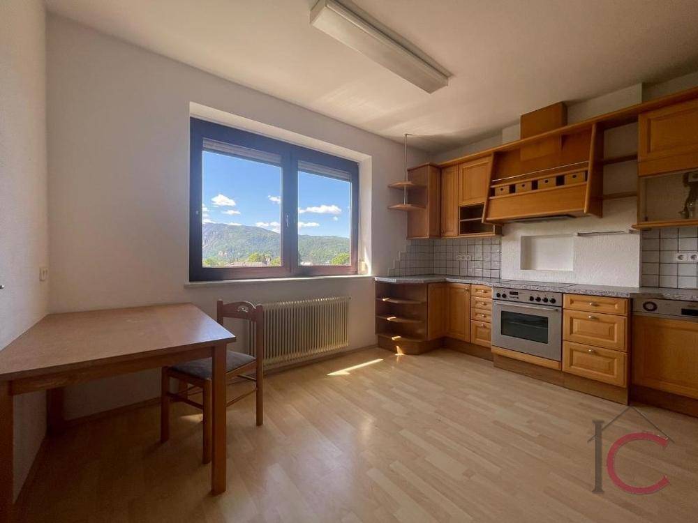 Geräumige Küche mit Holzeinbauten, Essbereich und großem Fenster mit Bergblick.