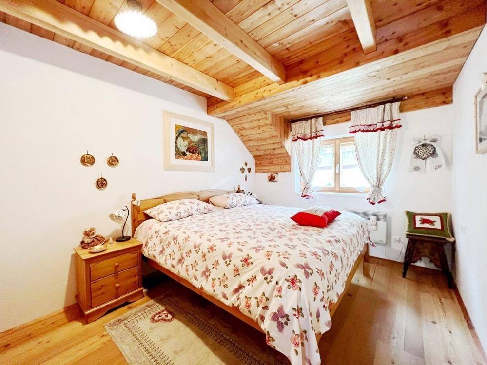 Gemütliches Schlafzimmer mit Holzbalkendecke, Doppelbett und traditionellen Akzenten.
