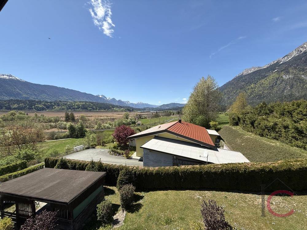 Großer Garten mit Hecke, Gartenhaus und weitem Blick auf die Berge und das Tal.
