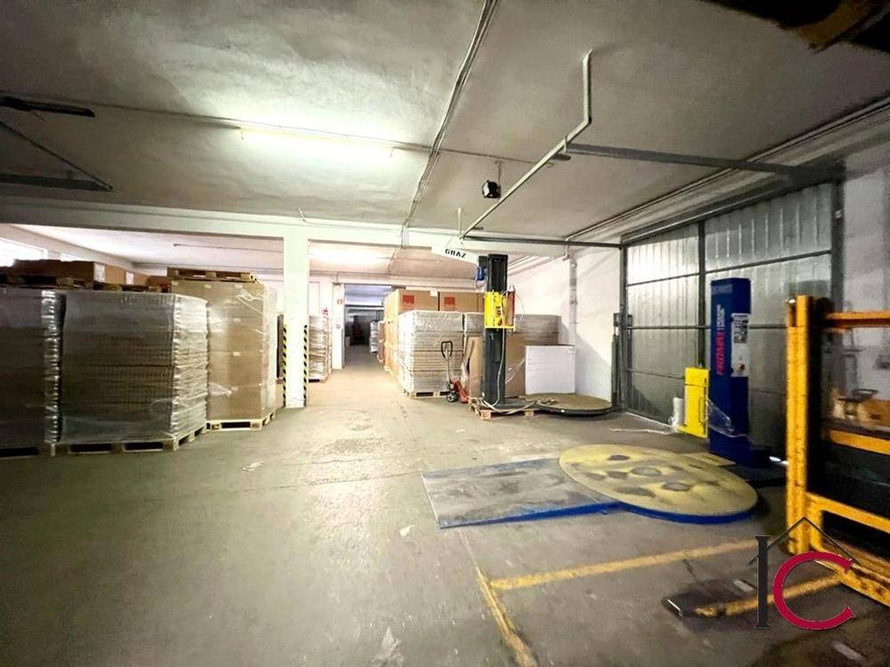 Geräumiger Lagerbereich mit hohen Decken, Paletten voller Waren und industrieller Beleuchtung.