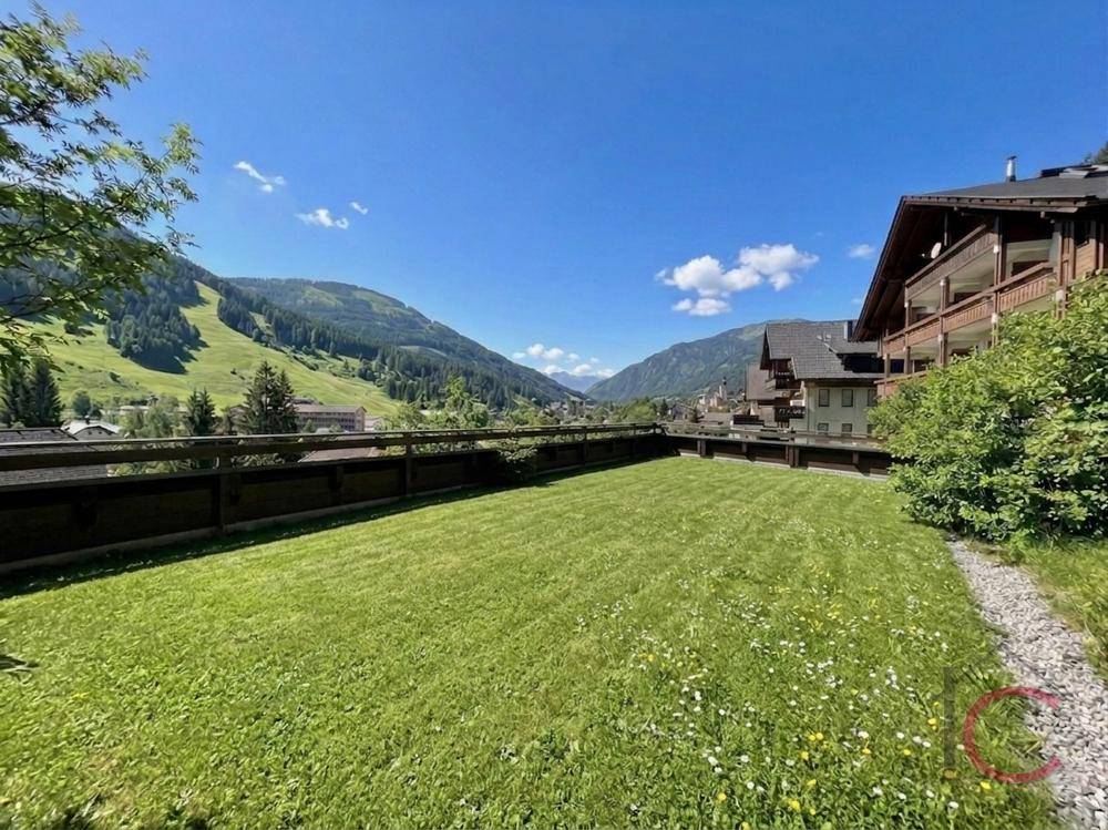 Gepflegter Rasenbereich mit weitem Blick auf die umliegende Berglandschaft und grüne Natur.
