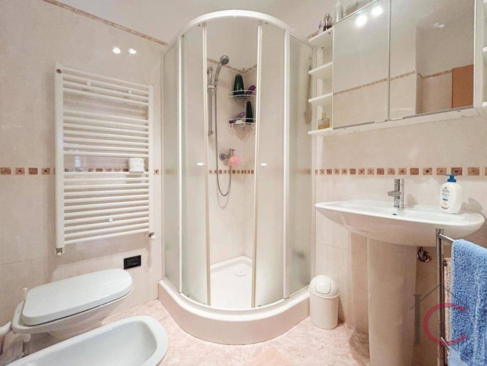 Badezimmer mit Duschkabine, WC, Bidet, Waschbecken und beheiztem Handtuchhalter.