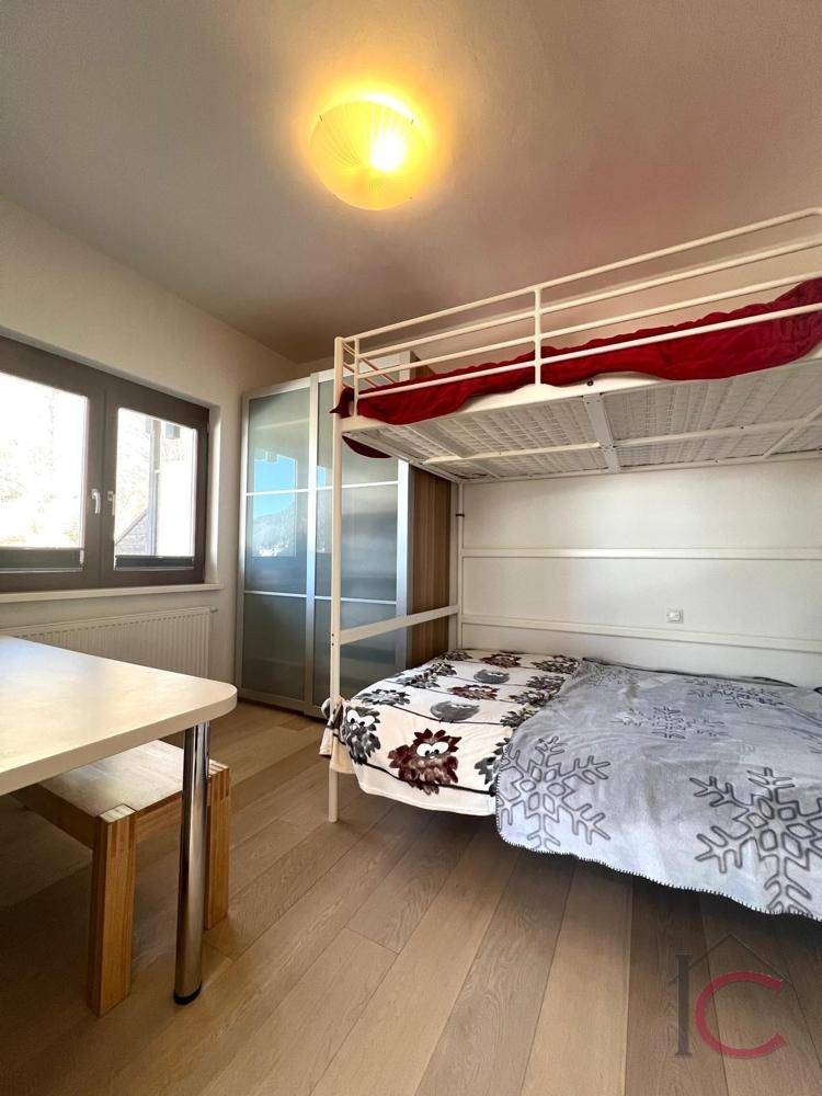 Schlafzimmer mit Etagenbett, Holzboden und Fenster für natürliches Licht.