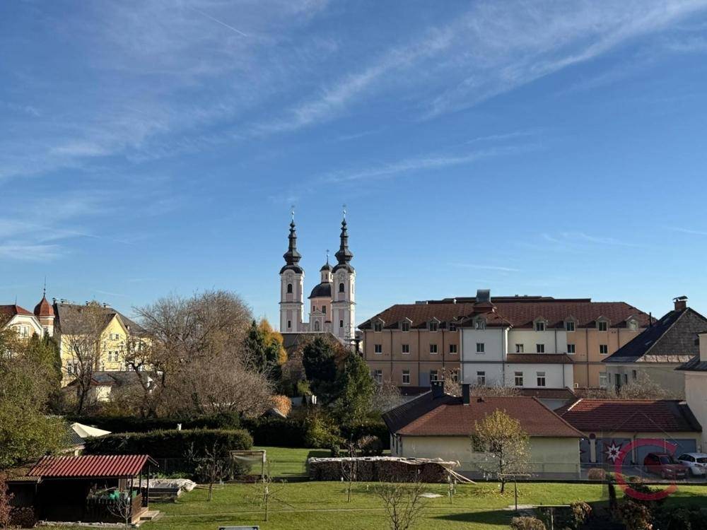 Panoramablick auf eine historische Kirche mit Zwiebeltürmen und die umliegende Landschaft unter blauem Himmel.