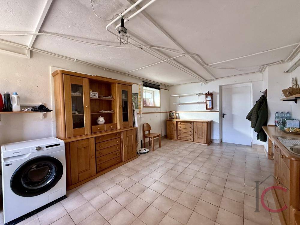Funktionaler Hauswirtschaftsraum mit Waschmaschine, Holzschränken und Fenster.