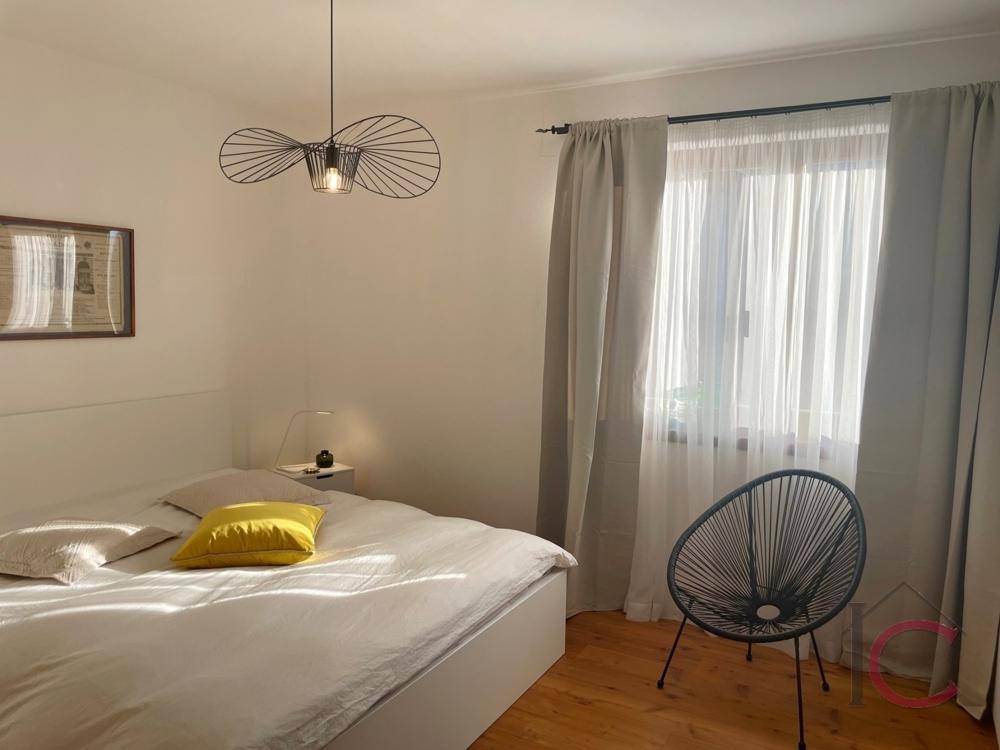 Helles Schlafzimmer mit Doppelbett, Holzboden und großem Fenster für viel Tageslicht.