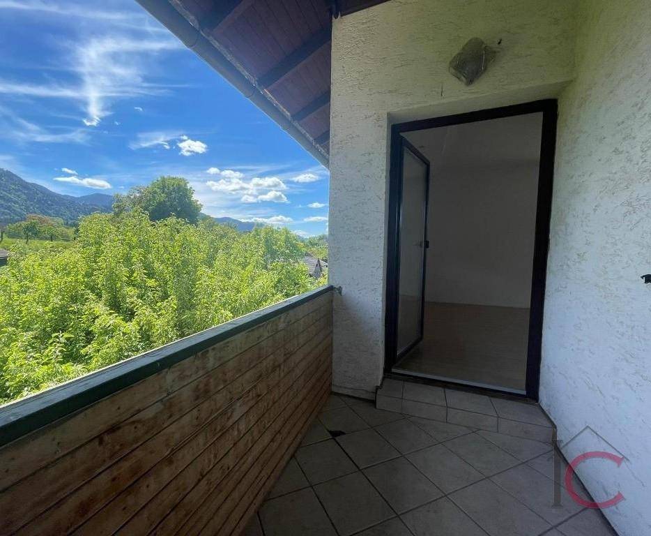 Heller Balkon mit Fliesenboden und Holzwand, bietet Zugang zu einem Innenraum.
