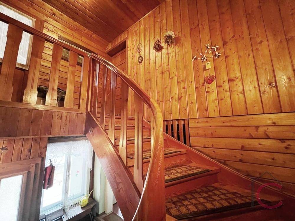 Rustikales Treppenhaus mit viel Holzverkleidung und einer geschwungenen Holztreppe.