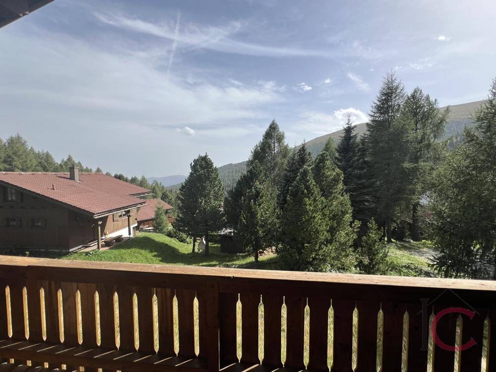 Balkon mit Panoramablick auf die grüne Bergwelt und weitere Chalets in der Ferne.