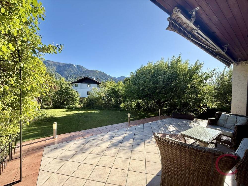 Große geflieste Terrasse mit Sitzgelegenheiten und weitem Blick auf die Berge und Natur.