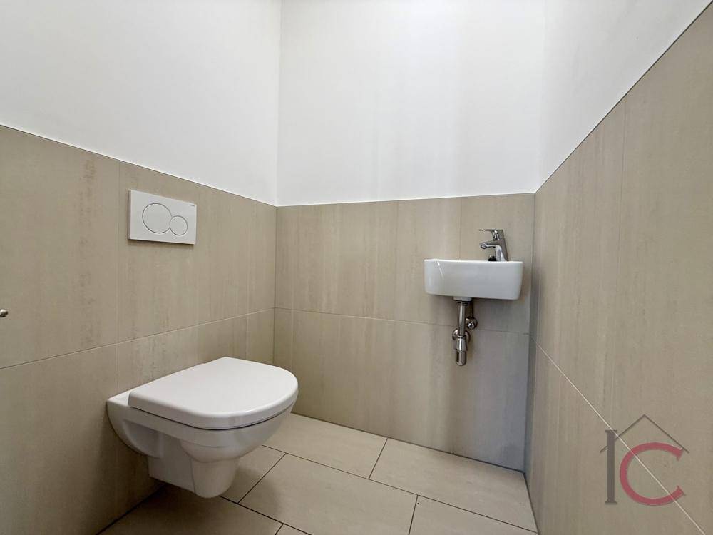 Separates Gäste-WC mit wandhängender Toilette und kleinem Handwaschbecken.