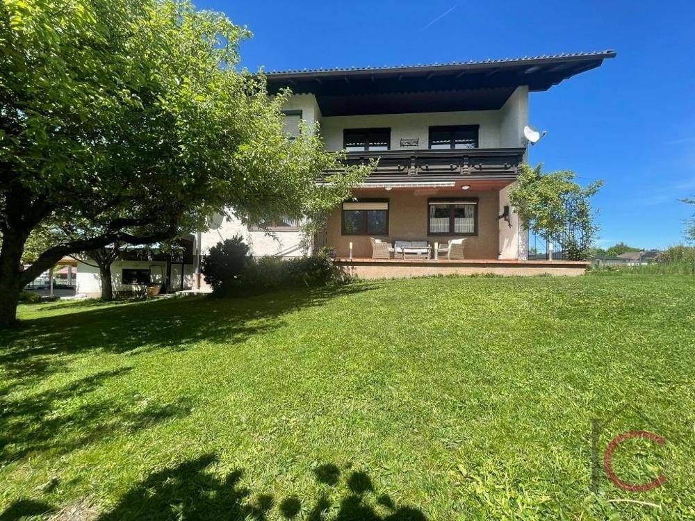 Freistehendes Einfamilienhaus mit großem Garten und Balkon, umgeben von viel Grün.