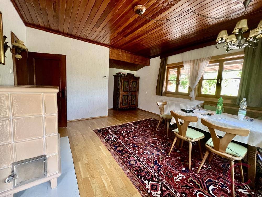 Essbereich mit traditionellem Kachelofen, Holzboden und rustikalem Teppich.