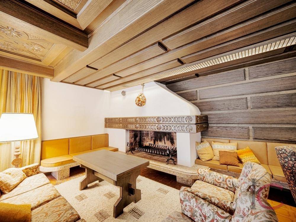 Wohnzimmer mit großem Kamin, Holzbalkendecke und gemütlicher Sitzecke.