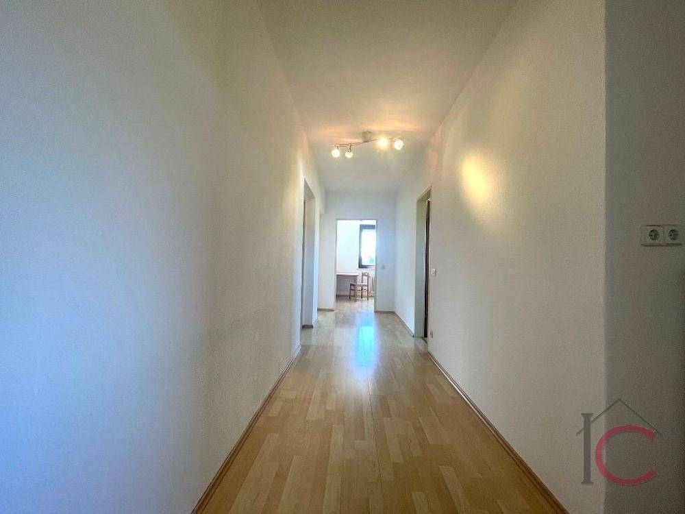 Langer, heller Flur mit Laminatboden, der verschiedene Zimmer miteinander verbindet.