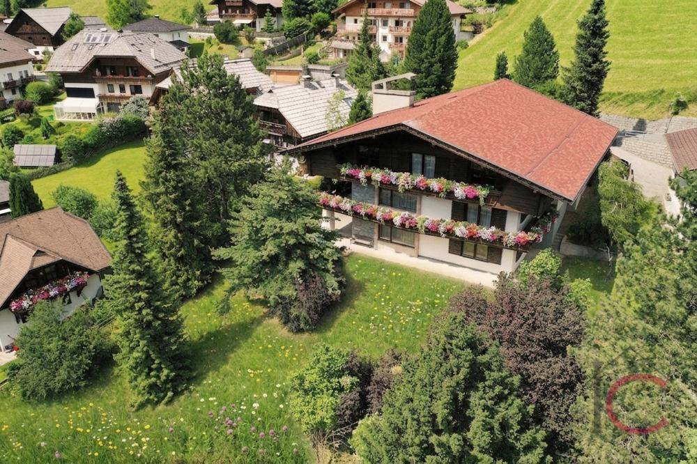 Vogelperspektive eines traditionellen Hauses mit rotem Dach und grüner Umgebung.