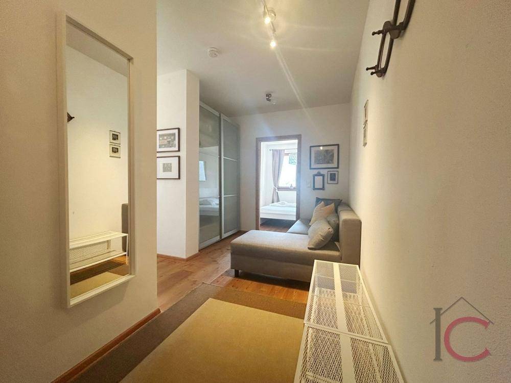 Heller Flur mit bequemer Chaiselongue, großem Spiegel und Zugang zu weiteren Wohnbereichen.