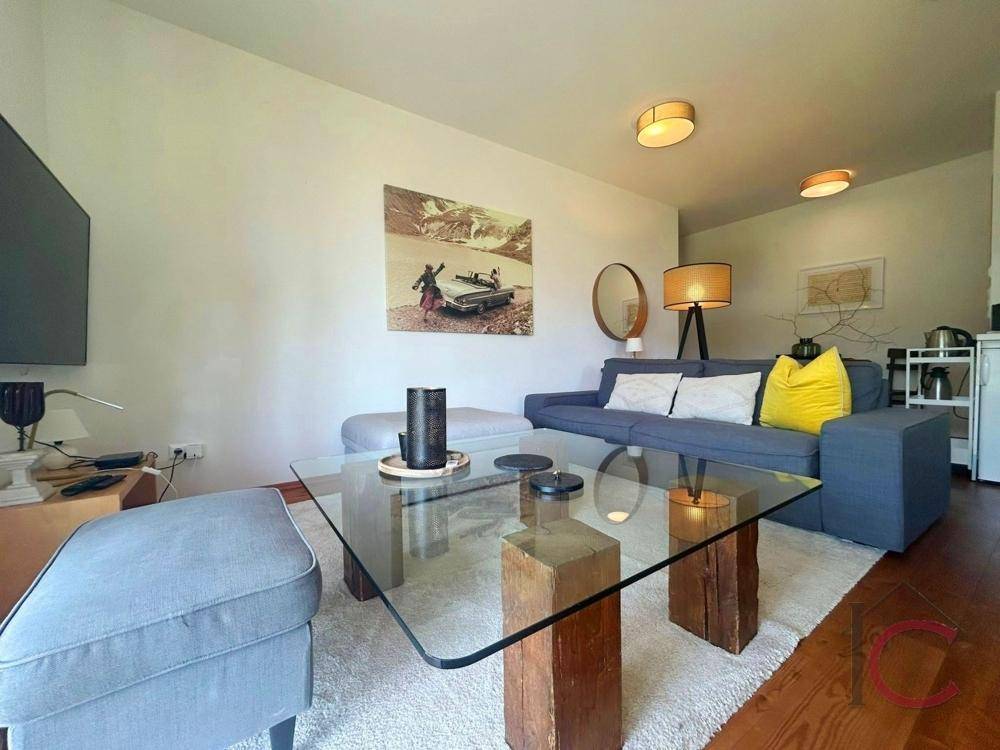 Gemütlicher Wohnbereich mit blauem Sofa, modernem Couchtisch und heller Einrichtung.