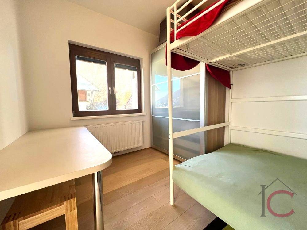 Helles Schlafzimmer mit Etagenbett, Schreibtisch und Fenster mit Blick ins Grüne.