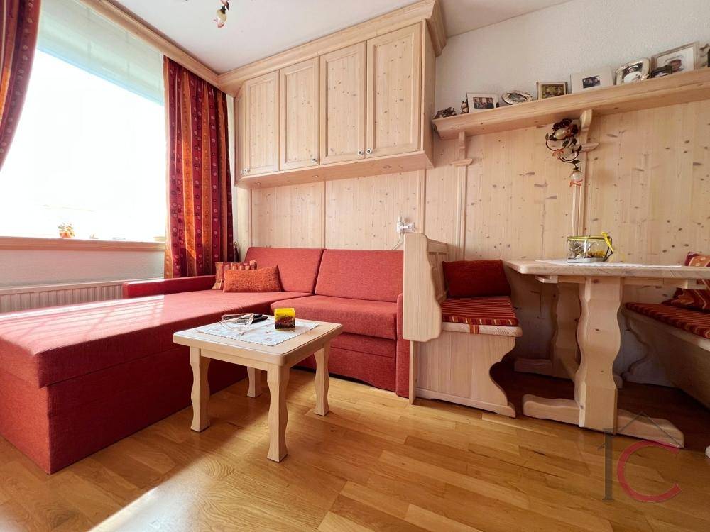 Traditionelles Wohnzimmer mit rotem Sofa, Holzvertäfelung und gemütlicher, heller Atmosphäre.