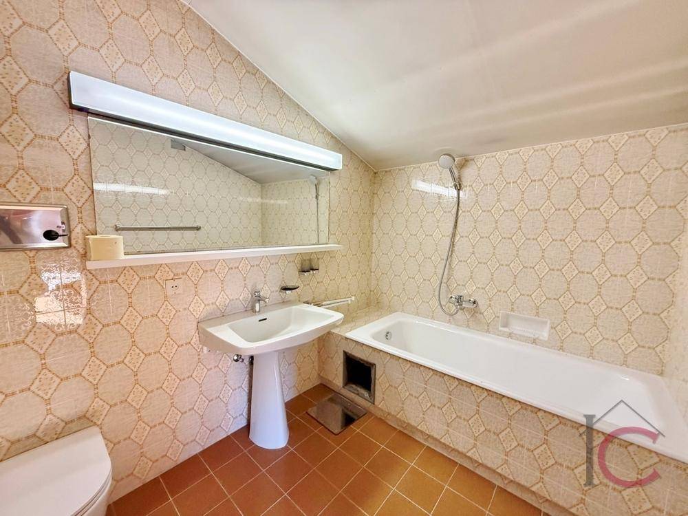 Badezimmer mit gemusterten Fliesen, Badewanne und Waschtisch.
