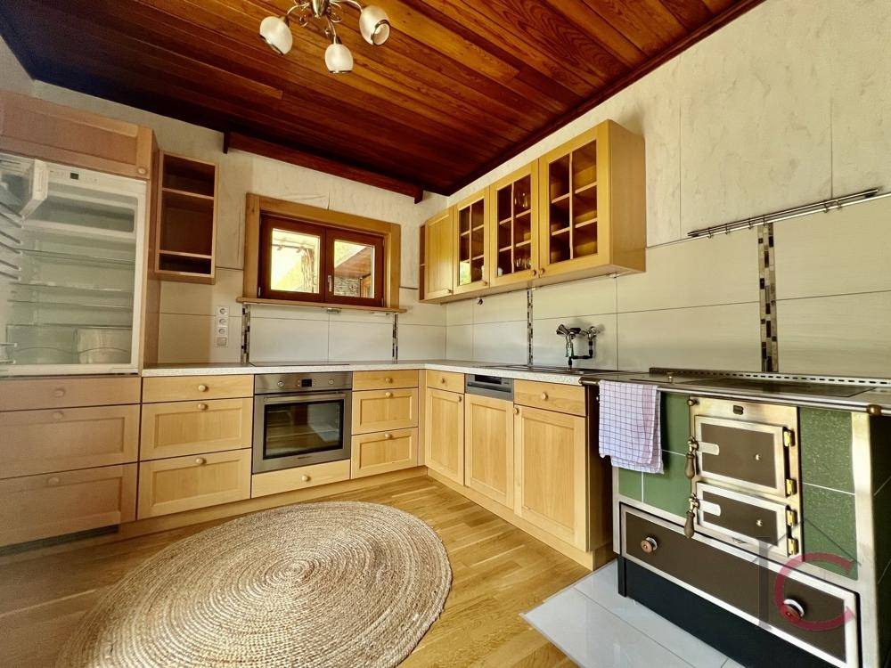Rustikale Küche mit Holzschränken, Einbaugeräten und traditionellem Holzherd.