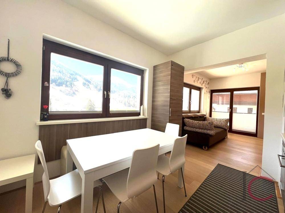 Heller Essbereich mit Holzboden und Bergblick, offen zum gemütlichen Wohnzimmer.