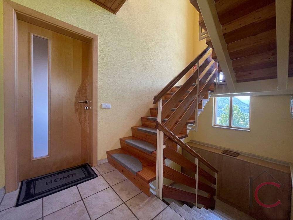 Eingangsbereich mit Holztreppe und gefliestem Boden, der zu den oberen Etagen führt.