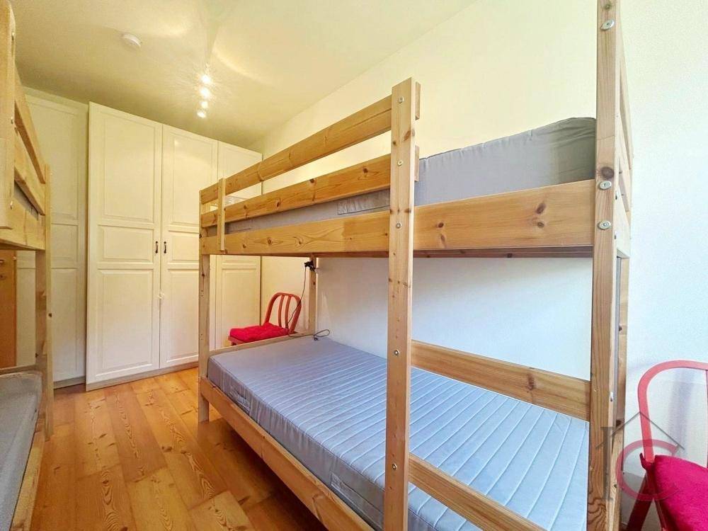 Kinderzimmer mit Etagenbetten, Holzboden und praktischen weißen Einbauschränken.