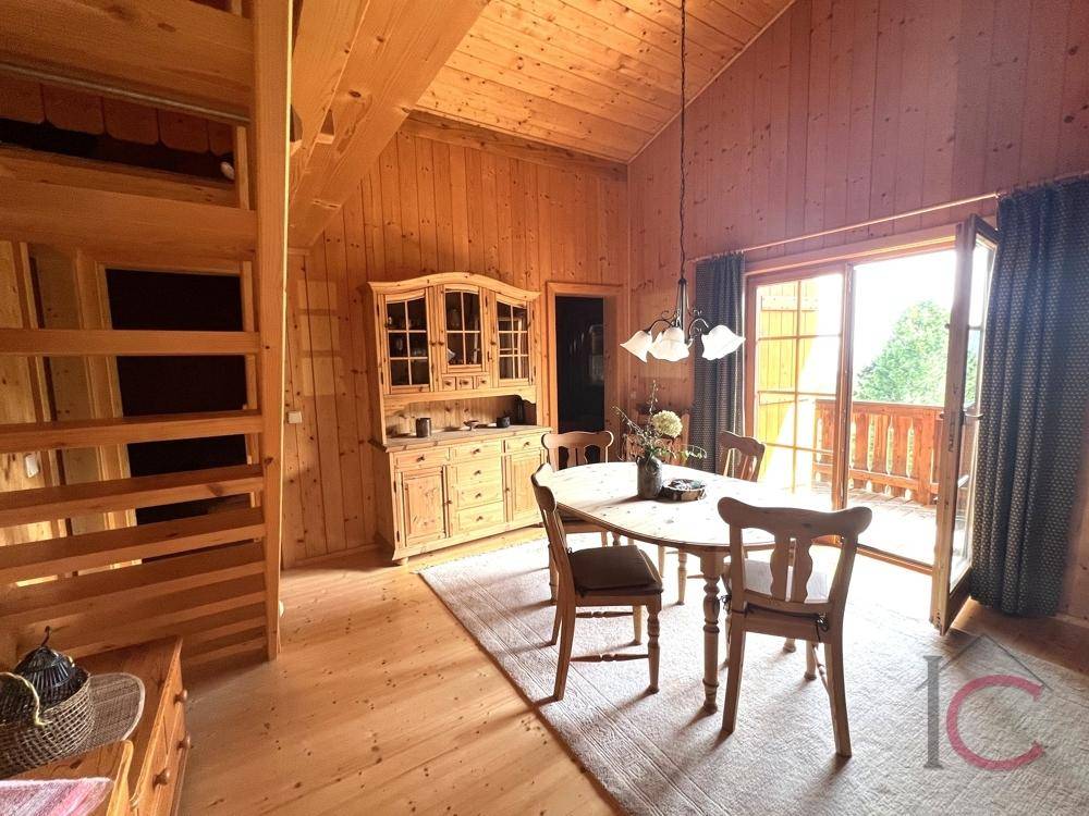 Gemütlicher Essbereich mit Holztisch, Stühlen und Zugang zu einem Balkon mit Bergblick.