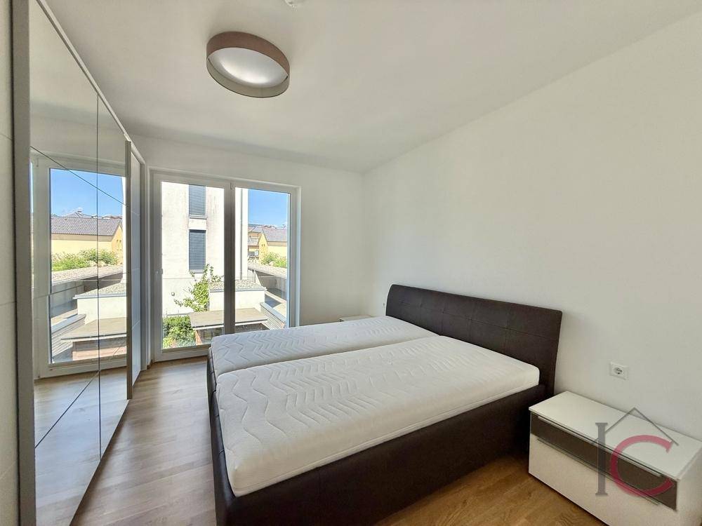 Helles Schlafzimmer mit Doppelbett, Einbauschränken und Zugang zu einem Balkon oder Terrasse.