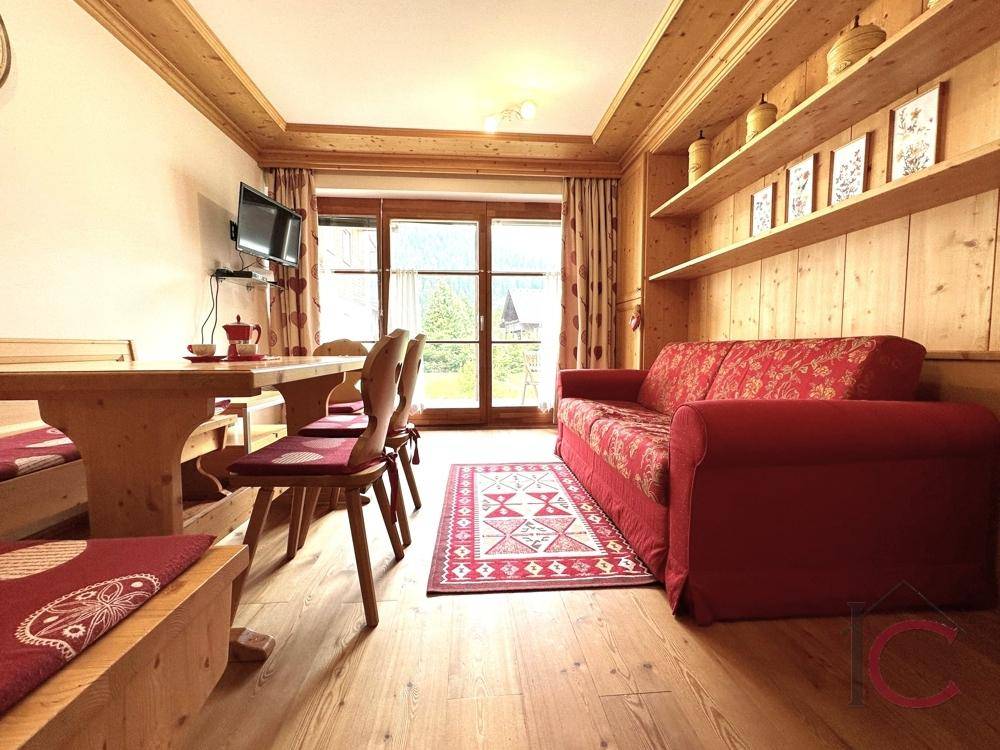 Traditioneller Wohn-Essbereich mit Holzboden, gemütlicher Sitzecke und Blick auf die Berglandschaft.