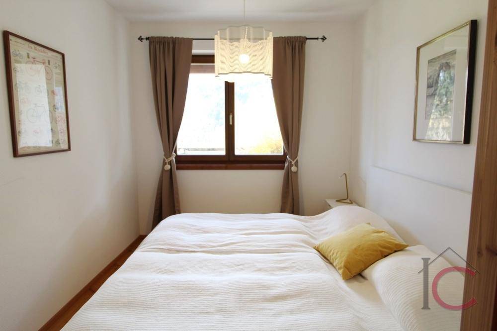 Ruhiges Schlafzimmer mit Doppelbett, Holzboden und Fenster mit braunen Vorhängen.