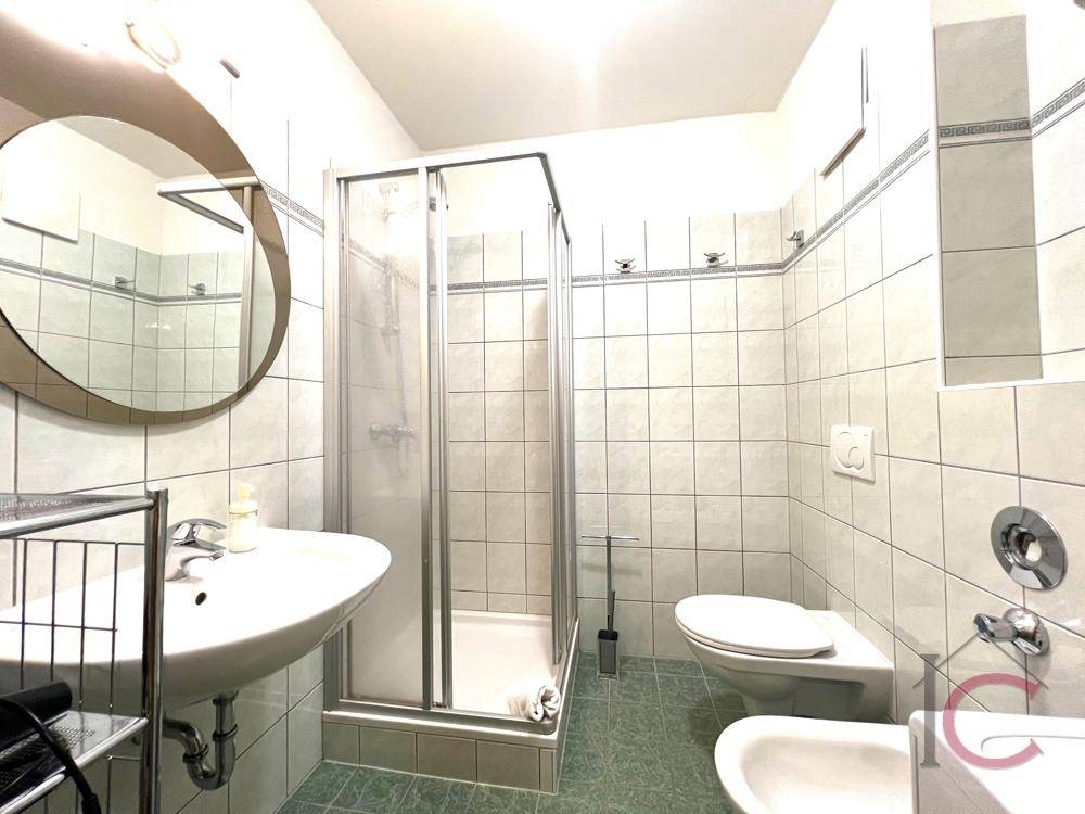 Funktionales Badezimmer mit Duschkabine, WC, Bidet und hellen Fliesen.