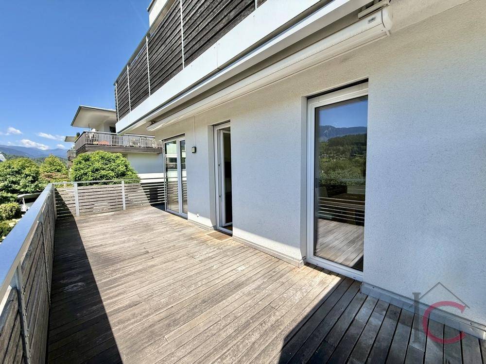 Weitläufige Holzterrasse mit Blick auf die grüne Umgebung und die umliegenden Häuser.