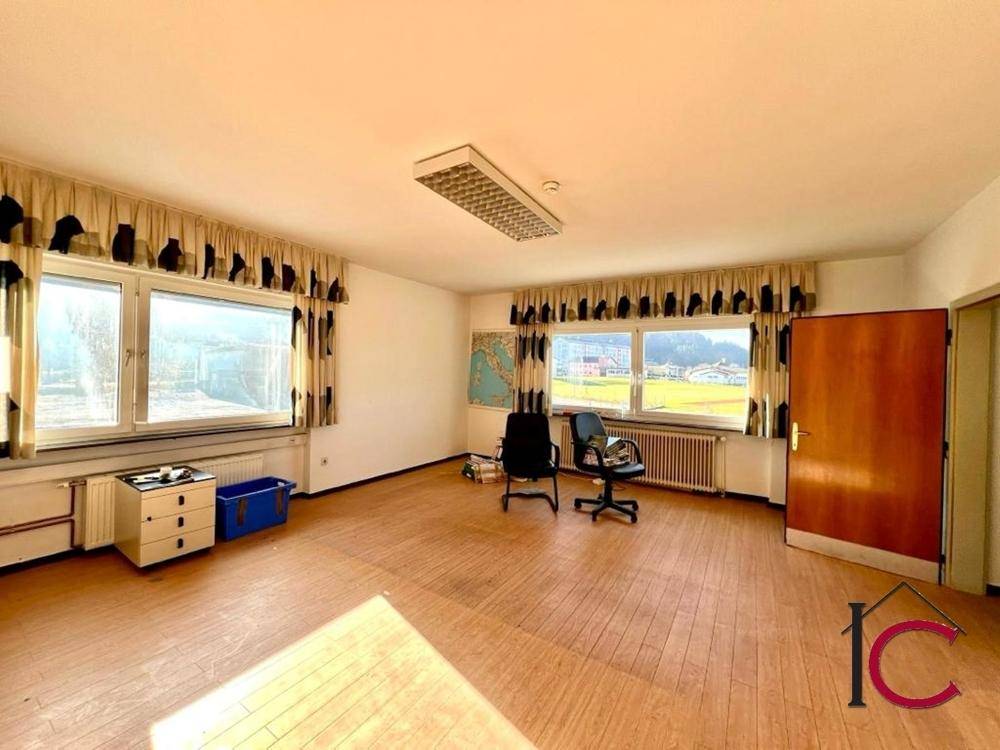 Weitläufiges Büro mit Holzboden, großen Fenstern und Blick auf die umliegende Landschaft.