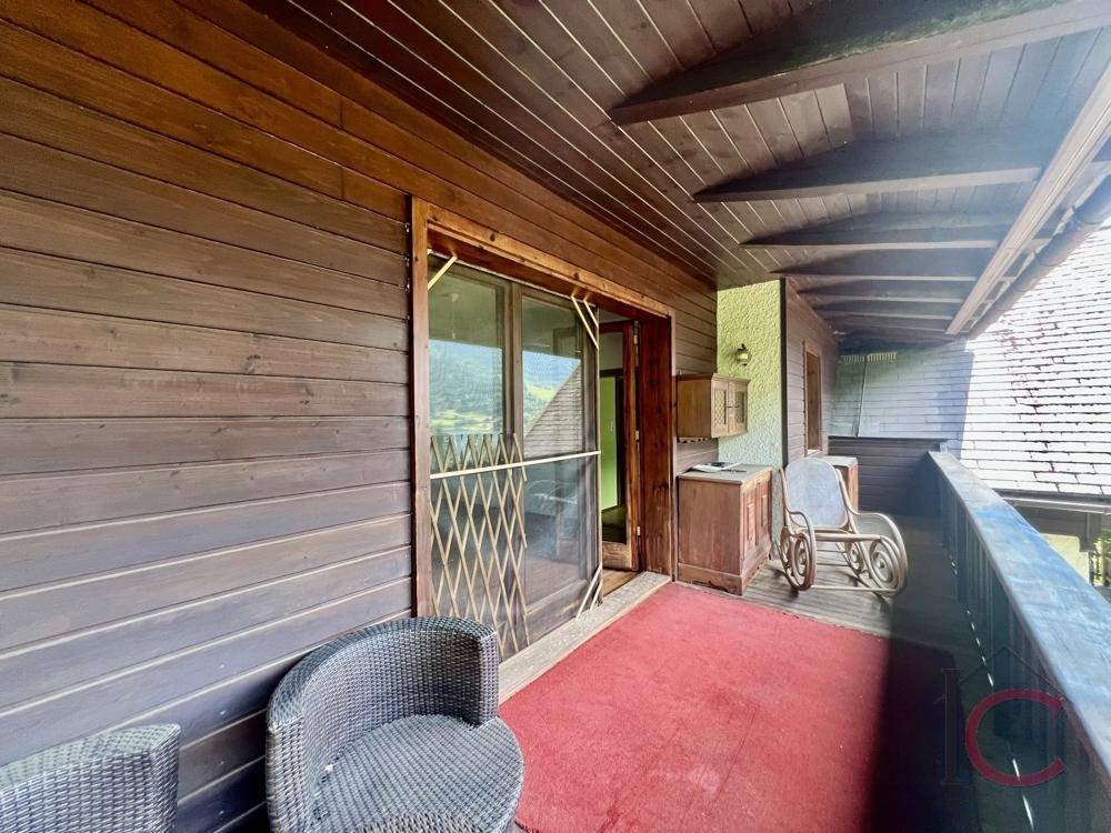 Überdachter Balkon mit gemütlichen Sitzgelegenheiten und Holzverkleidung.