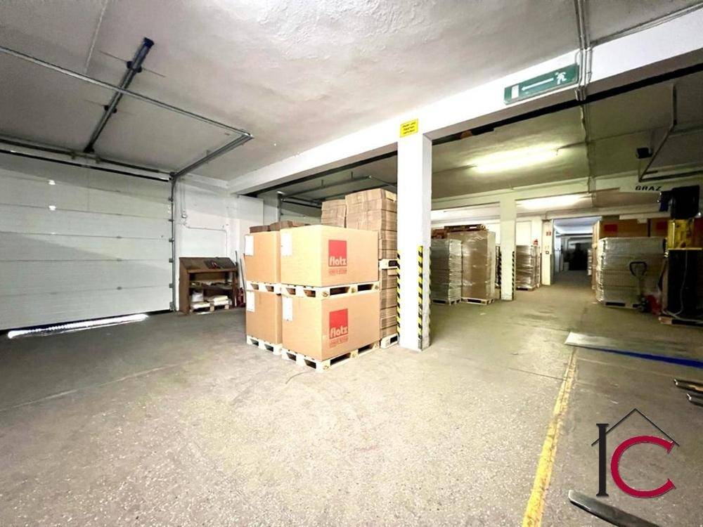 Lagerhalle mit Rolltor, hohen Decken und gestapelten Paletten voller verpackter Waren.