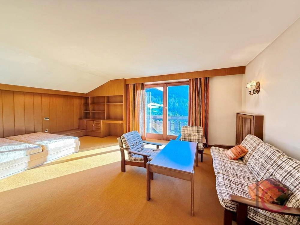 Schlafzimmer mit Teppichboden, Holzvertäfelung und Balkonzugang mit Bergblick.