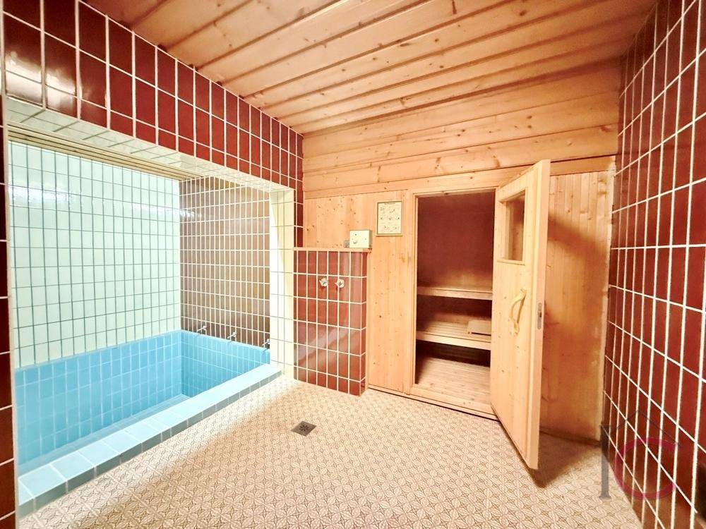 Wellnessbereich mit Sauna und kleinem Tauchbecken, umgeben von roten Fliesen und Holzdecken.