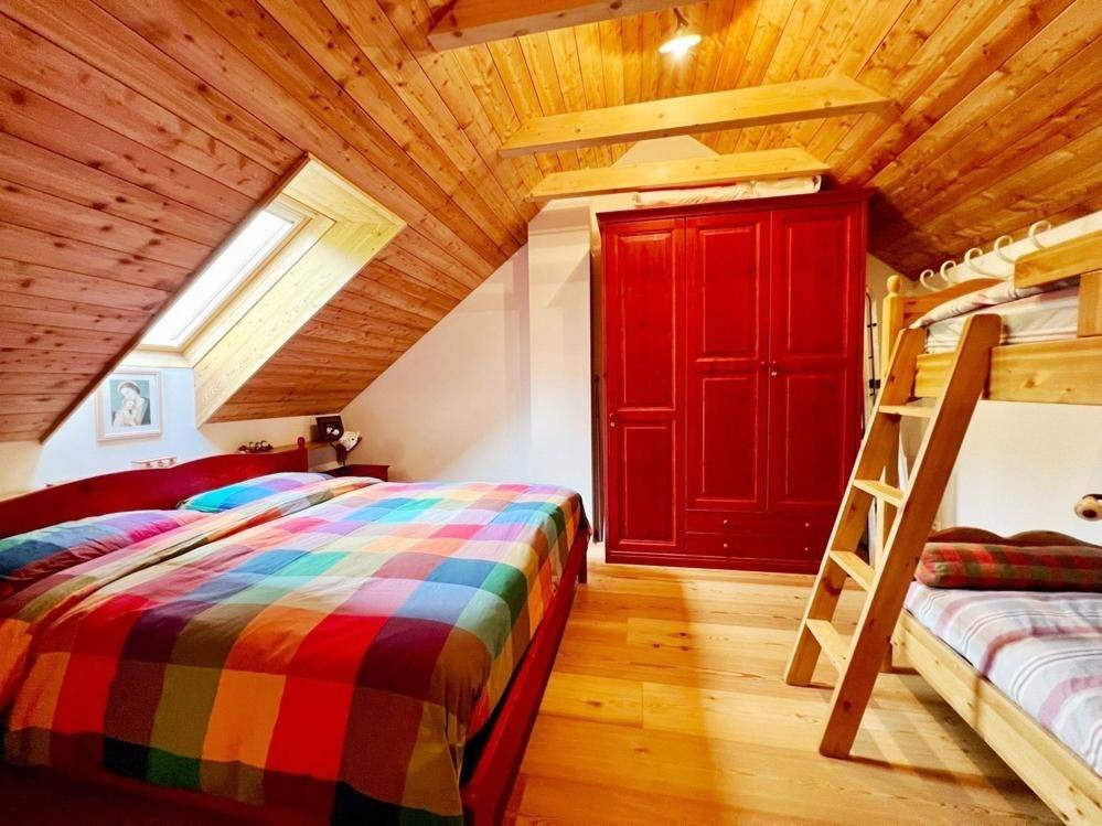 Helles Schlafzimmer mit Dachfenster, Holzboden und Etagenbett unter der Dachschräge.