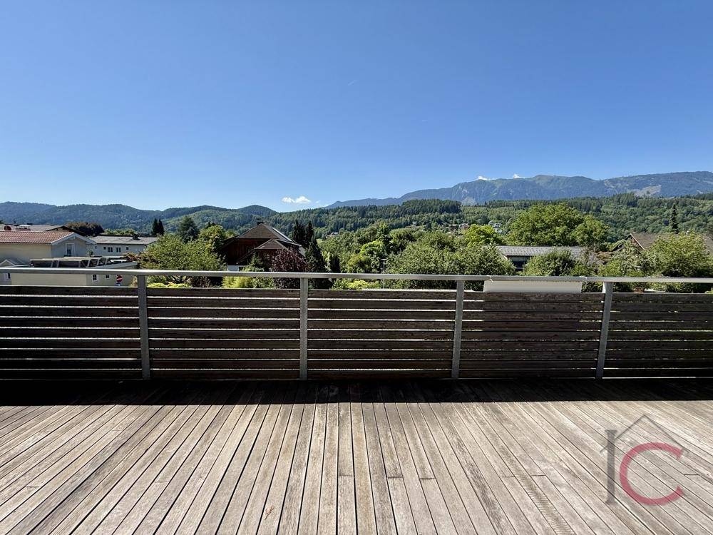 Große Holzterrasse mit Panoramablick auf die umliegende Berglandschaft und viel Grün.