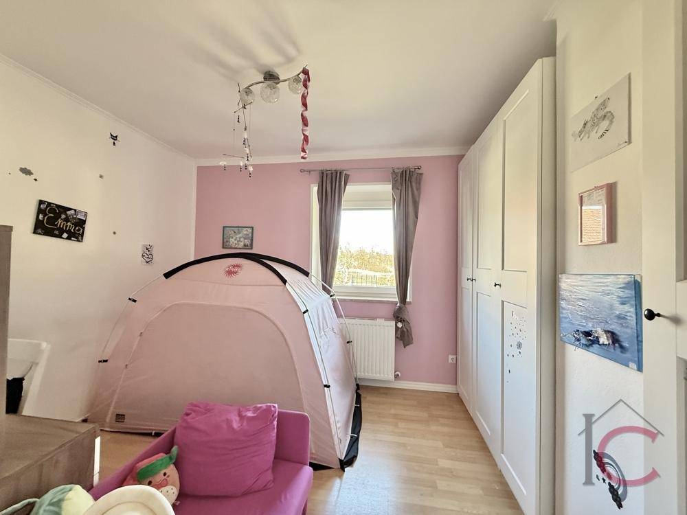 Kinderzimmer mit rosa Zelt, weißem Kleiderschrank und hellem Holzboden für spielerische Momente.
