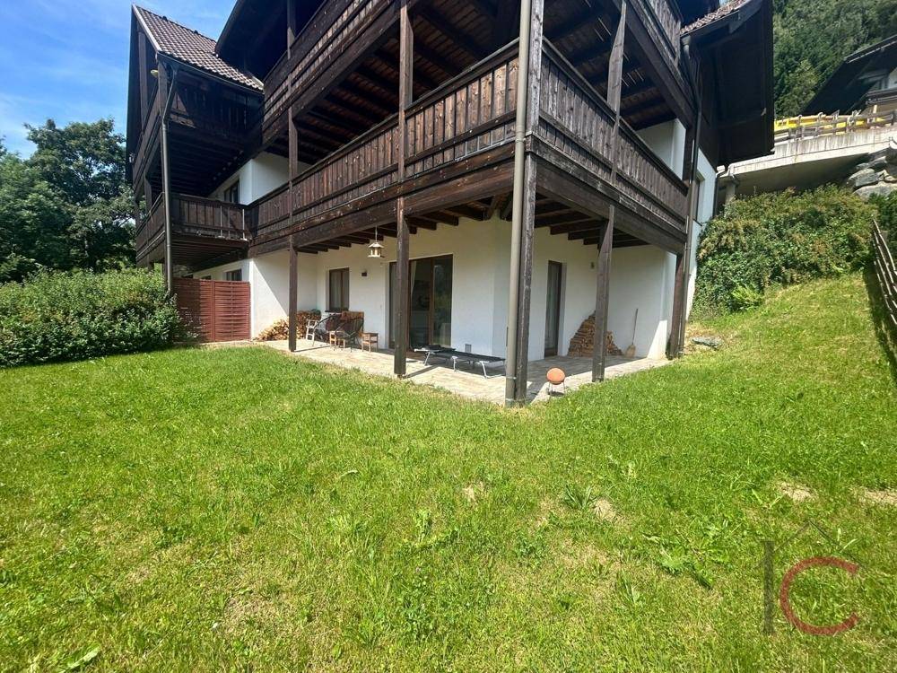 Außenansicht des Gebäudes mit großzügiger Rasenfläche und einer kleinen Terrasse im Erdgeschoss.