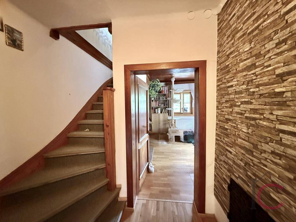 Eingangsbereich mit Holztreppe und dekorativer Steinwand, die zum Wohnbereich führt.