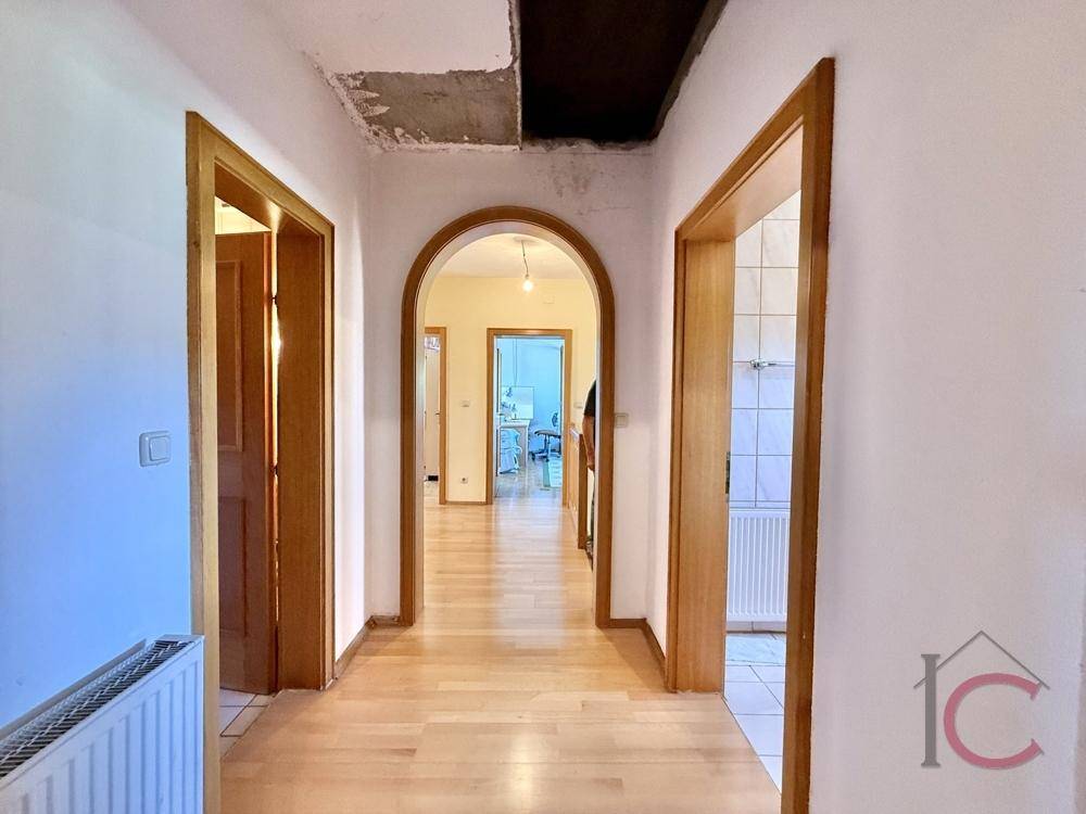 Flur mit Holzparkettboden, Holztüren und einem Bogen, der zu weiteren Räumen führt.